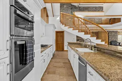 a kitchen with white cabinets and a spiral staircase at A California Country Experience - Tehachapi in Tehachapi