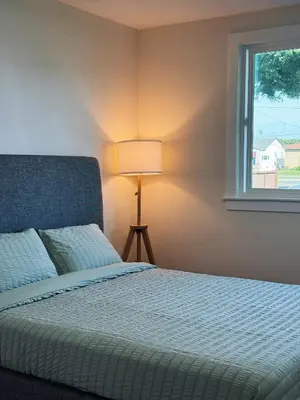 a bedroom with a bed with a lamp and a window at Cozy private Room D in S Central LA in Los Angeles