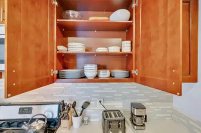 a kitchen with wooden cabinets with plates and utensils at High Ceilings 3BR with Loft-2 Baths Pool & Jacuzzi in Tarzana