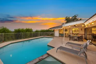 a swimming pool with a patio and a house at Off Grid Mountaintop Paradise Pool Spa and Games in San Bernardino