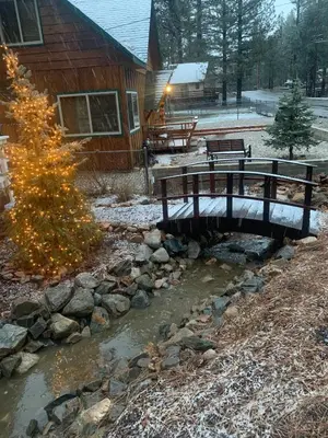 a wooden bridge over a stream in front of a house at Spacious cozy chalet huge deck over seasonal creek in Big Bear City Airport
