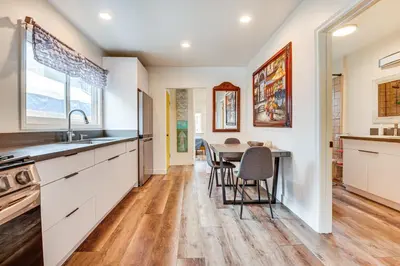 a kitchen with white cabinets and a table with chairs at Home 1 Mi to DTLA Room to Work and Relax! in Los Angeles