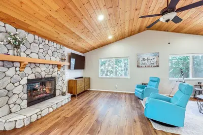 a living room with a stone fireplace and blue chairs at Swim, Hike, Ski and Unwind Lake Arrowhead Retreat! in Lake Arrowhead