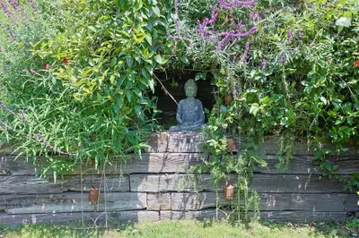 a statue sitting in a garden with plants at The Topanga Bungalow by Colby & Conrad in Topanga