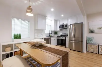 a kitchen with a table and a stainless steel refrigerator at Stylish Long Beach Retreat Walk to Beach Bars in Long Beach