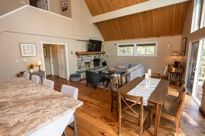 a dining room and living room with a table and chairs at Stunning secluded Creekside A-Frame gameroom in Lake Arrowhead