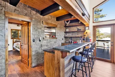 a kitchen with a stone wall and bar with stools at The Birdhouse at Big Bear Lake- Lakeview Family Retreat in Big Bear Lake