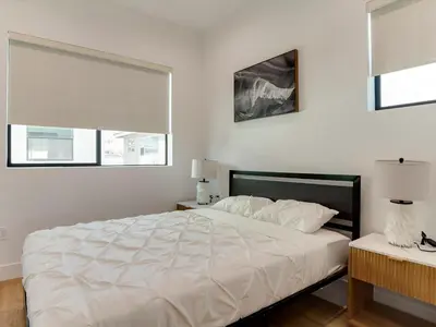 a bedroom with a large white bed and two windows at Modern Luxe Retreat Two-Bedroom in Los Angeles