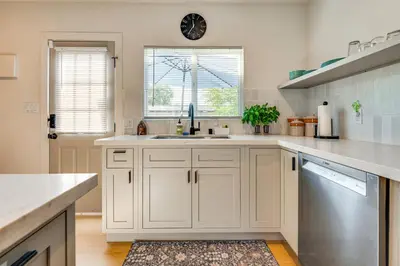 a kitchen with white cabinets and a sink and a window at 1 Mi to Rose Bowl! Updated Home with Furnished Deck in Pasadena