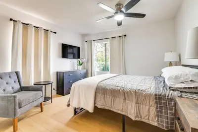a bedroom with a bed with a ceiling fan and a chair at 1 Mi to Rose Bowl! Updated Home with Furnished Deck in Pasadena