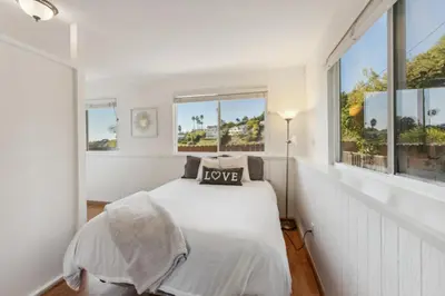 a white bedroom with a bed and windows at Whitney Oceanview Studio in Summerland