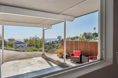 a living room with a view of the ocean through a window at Whitney Oceanview Studio in Summerland