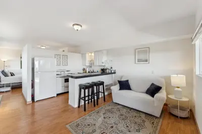 a living room with a white couch and a kitchen at Whitney Oceanview Studio in Summerland