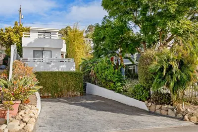 a house with trees and plants in front of a driveway at The Hidden Hideaway in Summerland