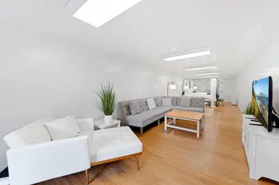 a living room with white furniture and a flat screen tv at The Hidden Hideaway in Summerland
