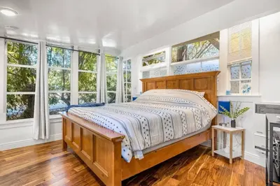 a bedroom with a large bed and windows at Jennifers Room - Pet Friendly in Summerland