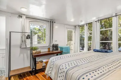 a bedroom with a bed and a desk and windows at Jennifers Room - Pet Friendly in Summerland