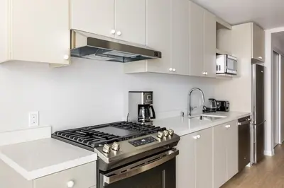 a kitchen with white cabinets and a stove top oven at Blueground Downtown elevator nr parks LAX-1245 in Los Angeles
