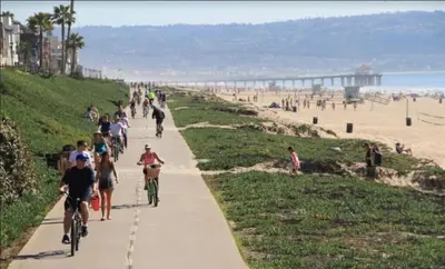 a group of people riding bikes on a sidewalk near the beach at Exclusive Ocean & Pier View Family Escape in Manhattan Beach