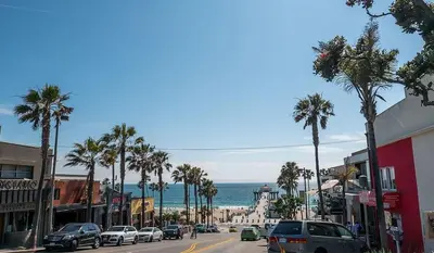 a busy city street with palm trees and the ocean at Exclusive Ocean & Pier View Family Escape in Manhattan Beach