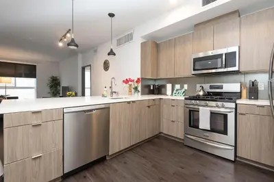 a kitchen with wooden cabinets and stainless steel appliances at Lovely 3BR Apt With Balcony And Rooftop Pool Plus Views in Los Angeles