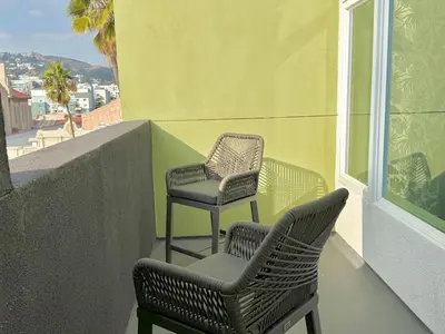 two chairs sitting on a balcony next to a window at Top Floor Hollywood 1BR Condo with Views in Los Angeles