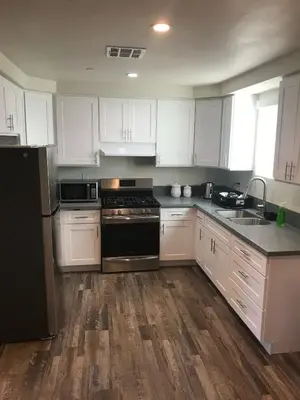 a kitchen with white cabinets and a black stove top oven at VWM Hostel in Los Angeles
