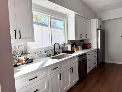 a kitchen with white cabinets and a sink and a window at 4 Bed Modern Pool House with Spa & Game Room in Northridge Hospital Heliport