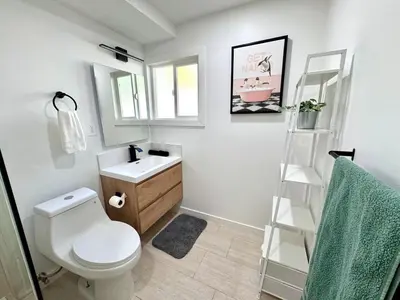 a bathroom with a white toilet and a sink at 4 Bed Modern Pool House with Spa & Game Room in Northridge Hospital Heliport