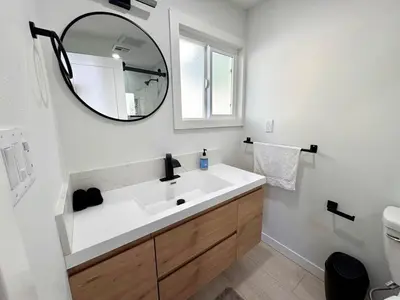 a bathroom with a white sink and a mirror at 4 Bed Modern Pool House with Spa & Game Room in Northridge Hospital Heliport