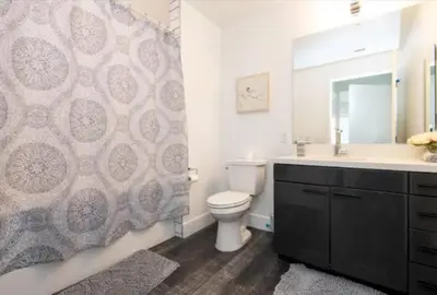 a bathroom with a toilet and a sink and a mirror at Modern 3 Bedroom High-Rise with resort Pool in Los Angeles