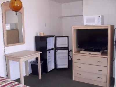 a living room with a television and a desk and a table at Budget Inn of Boron in Boron
