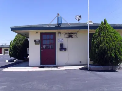 a building with a red door in a parking lot at Budget Inn of Boron in Boron