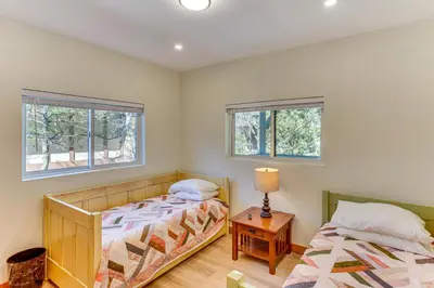two beds in a room with two windows at Game Room and Deck Pet-Friendly Lake Arrowhead Home in Lake Arrowhead