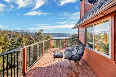 a balcony with a chair on a wooden deck at High-Top Lakeview Chateau Relaxing Modern Fawnskin Retreat in Fawnskin