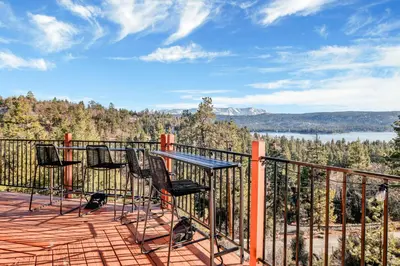 a deck with chairs and a table and a view at High-Top Lakeview Chateau Relaxing Modern Fawnskin Retreat in Fawnskin