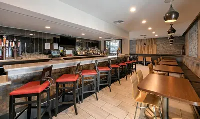 a bar with wooden tables and chairs in a restaurant at Pacific Stay Hotel in West Covina
