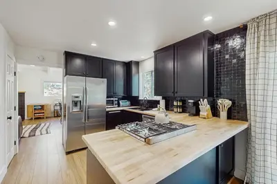 a kitchen with black cabinets and a wooden counter top at Arrowhead Aura in Lake Arrowhead