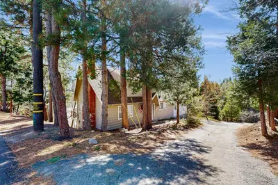 a house with a lot of trees in front of a road at Arrowhead Aura in Lake Arrowhead
