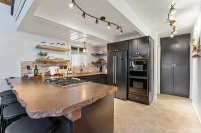 a kitchen with a large stone counter top and stainless steel appliances at Cozy Owl Lodge, Central AC & Hea, Spa Tub & BBQ in Lake Arrowhead