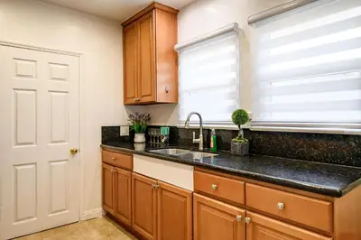 a kitchen with wooden cabinets and a sink and a window at Comfortable Home Near LA with Full Kitchen & Laundry in Alhambra