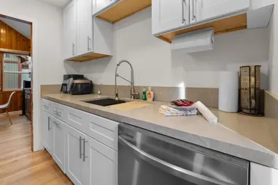 a kitchen with white cabinets and a stainless steel sink at Big Bear Cottage - Walk to Lake, Smart TV, Fireplace, Deck in Big Bear Lake