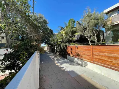 a sidewalk next to a fence and trees at King Oasis - steps to beach with garden patio! in Los Angeles