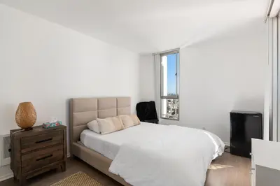 a white bedroom with a bed and a television at The violet-Santa Monica highrise beach front&view in Los Angeles