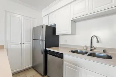 a kitchen with white cabinets and a stainless steel refrigerator at The violet-Santa Monica highrise beach front&view in Los Angeles