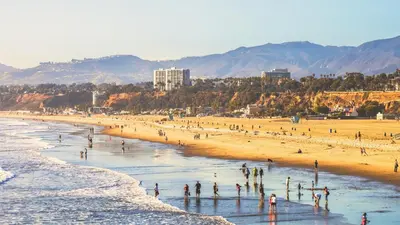 a group of people standing on a beach at The violet-Santa Monica highrise beach front&view in Los Angeles