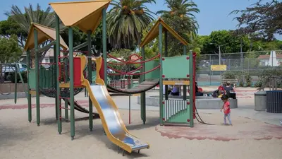 a child standing in front of a playground at The violet-Santa Monica highrise beach front&view in Los Angeles