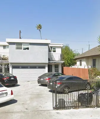 a white house with cars parked in a parking lot at Cultura Homes On Crawford in Los Angeles