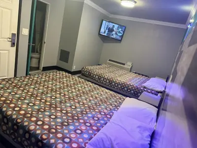 a room with two beds and a tv on the wall at Bob's Motel in Commerce