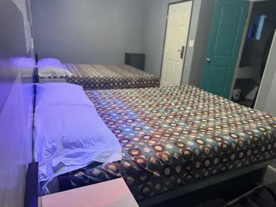 two beds in a room with purple sheets and a door at Bob's Motel in Commerce